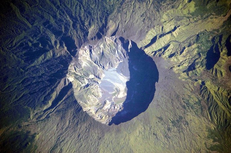 volcano erupting with an ash cloud over an island