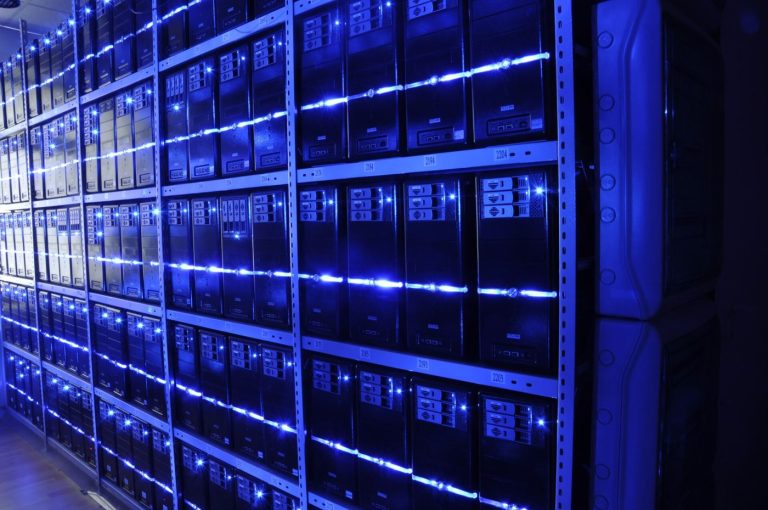 Sensors Help Engineers Spot Data Center Failures Early An engineer walking between rows of servers in a data center checking systems and cabling.